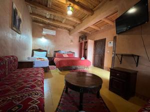 een kamer met twee bedden en een tafel en een televisie bij Palais D'Ouzoud in Azilal