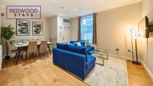 a living room with a blue couch and a table at Newly Refurbished Spacious Serviced Apartment for Contractors and Families, Free WiFi & Netflix By Redwood Stays in Farnborough