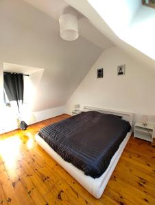 sypialnia z czarnym łóżkiem na poddaszu w obiekcie Cosy Triplex 3 chambres w mieście Pont-de-lʼArche