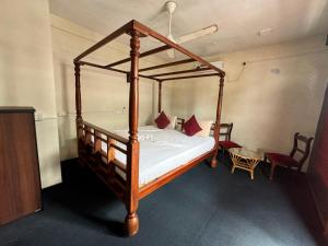 a bedroom with a wooden canopy bed with red pillows at Luthmin River View Hotel in Alutgama