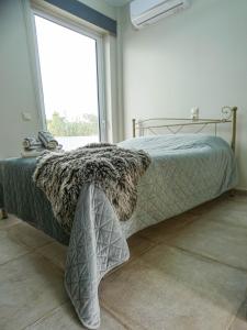 a bed in a room with a large window at MG Studio Kineta in Kineta