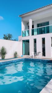 a villa with a swimming pool in front of a house at Pousada Sol e Mar Cabo Frio in Cabo Frio