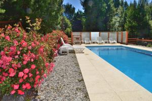 a swimming pool in a yard with pink flowers at Cabañas Villa Labrador con costa de lago in San Carlos de Bariloche