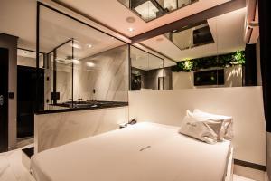 a bedroom with a white bed and a bathroom at Motel Jardim Secreto in Santo André