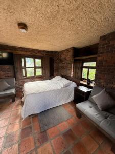 a bedroom with a large bed and a couch at El Agrado Restaurante Cabañas in Líbano