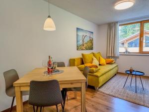 a living room with a yellow couch and a table at Ferienwohnung 5-Täler in Bartholomäberg