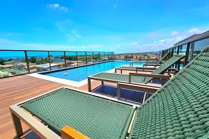 a swimming pool with green chairs and tables on a building at Rooftop Tamandaré by Temporada Inn in Tamandaré