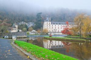 a large white building next to a river at Gite d'ici et d'ailleurs in Brantôme