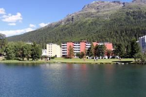a building next to a lake in front of a mountain at Skyline House Ferienapartments in St. Moritz +2 photos