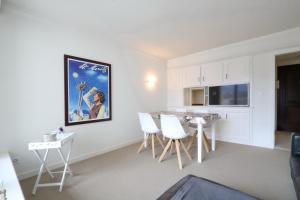 Una cocina con gabinetes blancos y una mesa y sillas. en Au Reduit 401, en St. Moritz