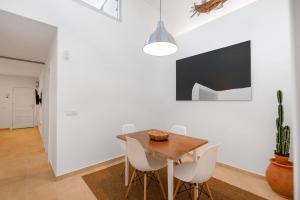 a dining room with a wooden table and white chairs at Casa Fela in Famara
