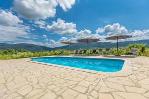 a swimming pool with umbrellas and mountains in the background at Villa Hills in Janja Gora