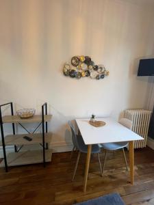 une table et des chaises dans une pièce avec une plaque sur le mur dans l'établissement Opale 1, à Vichy