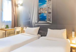 ein Hotelzimmer mit zwei Betten und einem Tisch in der Unterkunft B&B HOTEL Saint-Malo Centre in Saint-Malo + 37 Fotos