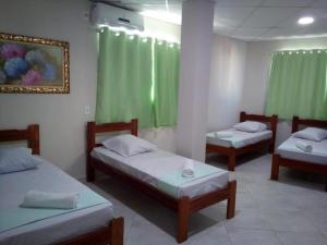 Tres camas en una habitación con cortinas verdes. en Hotel do Papa II, en Aparecida