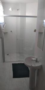 Un baño blanco con ducha y lavabo. en Hotel do Papa II, en Aparecida