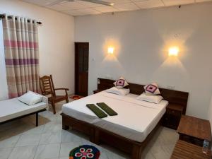 a bedroom with two beds and a table and chairs at Weaver Bird Villa in Habarana
