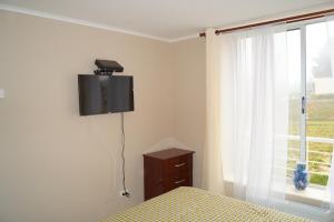 a bedroom with a bed and a tv on the wall at Laguna Bahia Fernanda in Algarrobo