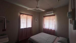 a small bedroom with two windows and a bed at Atbas Homestay No 1 in Seri Iskandar