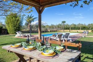 アルゲーロにあるLarge Villa Mediterranea in the heart of Coral Shore with swimming pool large garden with palm treesの食べ物とワインの皿が置かれた木製のテーブル