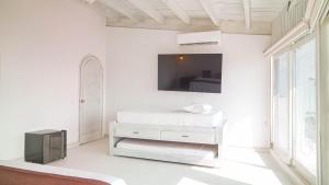 a white bedroom with a bed and a tv on the wall at Wala Hotel and Beach Club in Cartagena de Indias