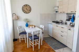 una cocina con mesa y sillas y un reloj en la pared en Home-Like Studio Walking Distance to the Old Town l Washing Machine l Bus Station Nearby, en Novi Sad