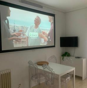 a projection screen on a wall with a table and chairs at 2 Habitaciones con vistas y 2 Terrazas en Primera Linea Playa Samil in Vigo