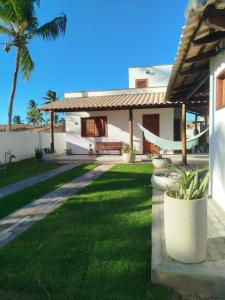 a house with a green yard with a hammock at Xalé da Xica in Amontada