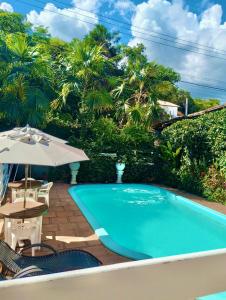 a swimming pool with a table and an umbrella at Pousada das Arvores in Lençóis