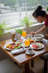 a woman sitting at a table with plates of food at Sea Phoenix Hotel Da Nang in Danang