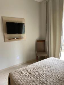 Un dormitorio con una cama y un televisor en la pared. en Apartamento villa serrano, en Lençóis
