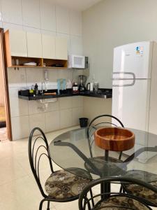 Una mesa de cristal y sillas en una cocina con frigorífico. en Apartamento villa serrano, en Lençóis