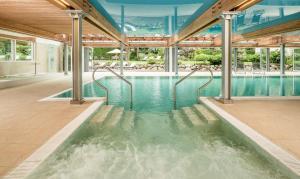 an indoor swimming pool with water in a building at Classic Hotel Meranerhof in Merano
