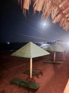 two chairs and an umbrella on a beach at night at H0TELIER Home, Máncora in Máncora +94 photos