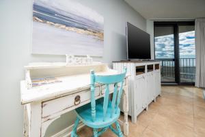 a desk with a television and a blue chair at Phoenix VI 6312 in Orange Beach +56 photos