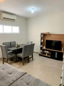 a living room with a table and chairs and a television at Triplex em Caraguatatuba! Alto padrão in Caraguatatuba