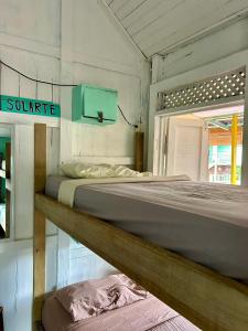 two beds in a white room with a sign on the wall at The Bocas Corner in Bocas Town