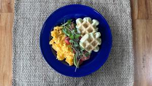 a blue plate with eggs and waffles and a salad at Lodge Paraíso Verde in Manizales +56 photos