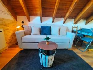 a living room with a white couch and a table at Le Nid Mansardé in Ustou