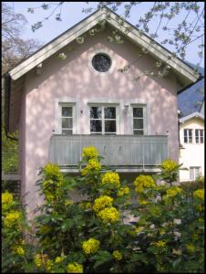 ein rosafarbenes Haus mit einer Veranda und gelben Blumen in der Unterkunft Ferienwohnung am Ortenaupark in Bad Reichenhall