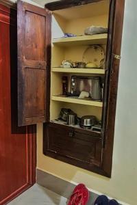 an open cabinet with pots and pans in a room at ATITHI HOMESTAY - Entire 2BHK in Central Bolpur with Private Parking - Pet Friendly in Bolpur
