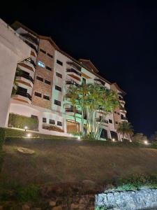 a building at night with palm trees in front of it at Piemont Flat Apart in Serra Negra