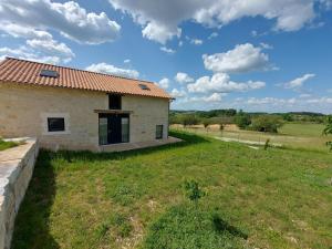 a stone house with a red roof in a field at Maison climatisée avec terrasse et Wi-Fi, animaux admis, proche Périgord Vert - FR-1-616-391 in Sorges
