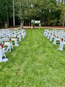 a row of white chairs sitting in the grass at Whisper Chateau Weddings Reunions Groups 75 Plus in Greensboro