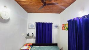 a bedroom with blue curtains and a ceiling fan at Munnar Hills And Mist Views in Anachal