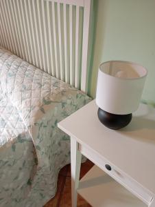 a lamp on a white table next to a bed at Ca L'Aida Rural 2 in Montblanc +7 photos