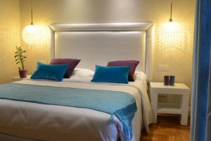 チャンピーノにあるラ ビレッタ スイートのベッドルーム1室(大型ベッド1台、青と紫の枕付)