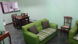 a living room with a green couch and a table at Aconchego in Paraty +4 photos