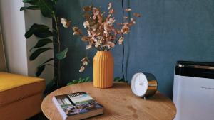 a table with a vase of flowers and a book at Self Check-IN Free Parking Near Metro Stations and BUS WestSide Studio S6 in Bucharest