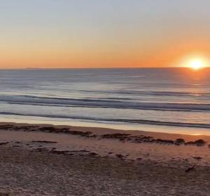 una puesta de sol sobre una playa con el océano en 30 Elizabeth, en Sawtell